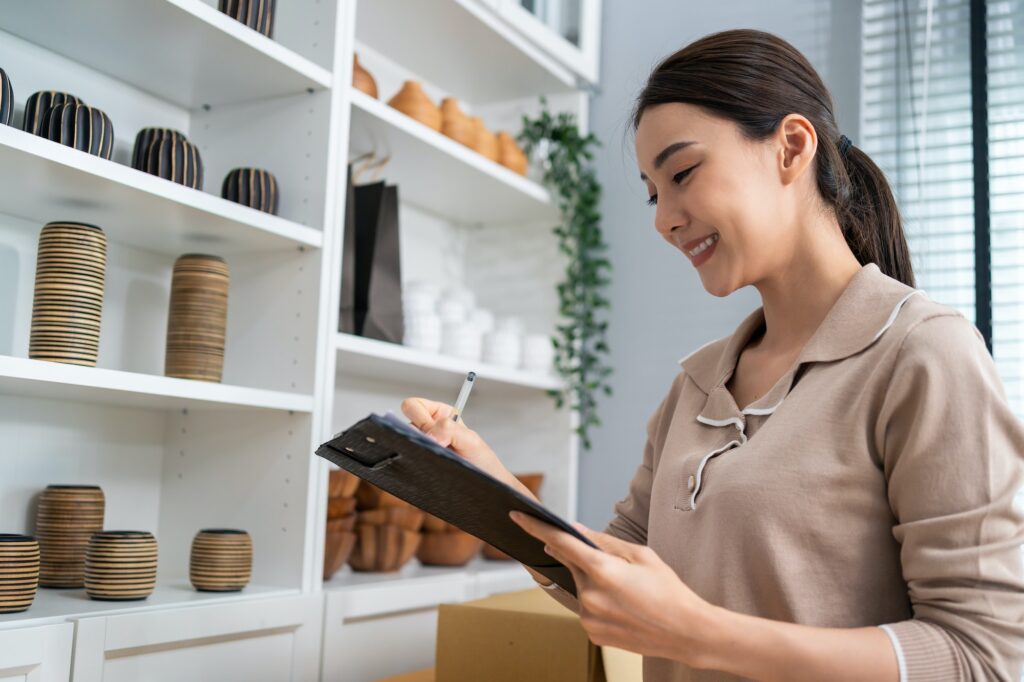 Asian beautiful woman check vase goods order for customer from shelf.