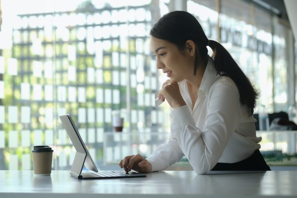 Attractive woman holding credit card and using computer tablet for online shopping.